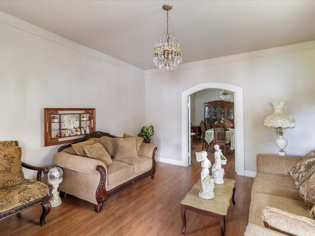 living room with a notable chandelier, wood-type flooring, and ornamental molding