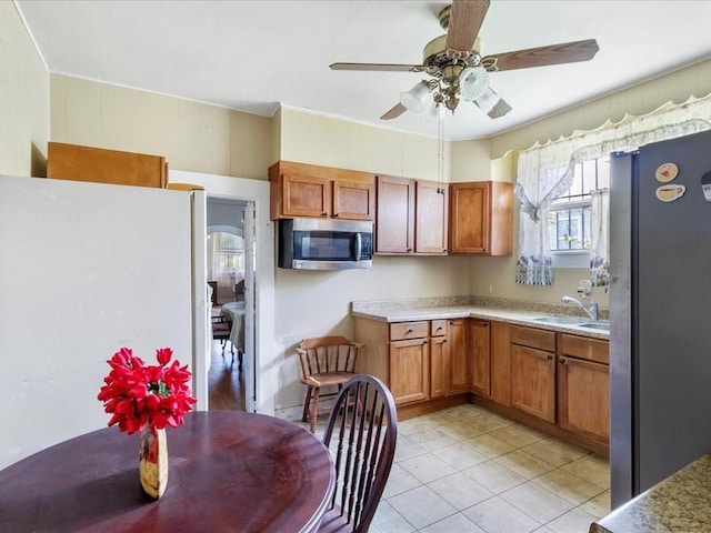 kitchen featuring sink, light tile patterned floors, ceiling fan, and white fridge