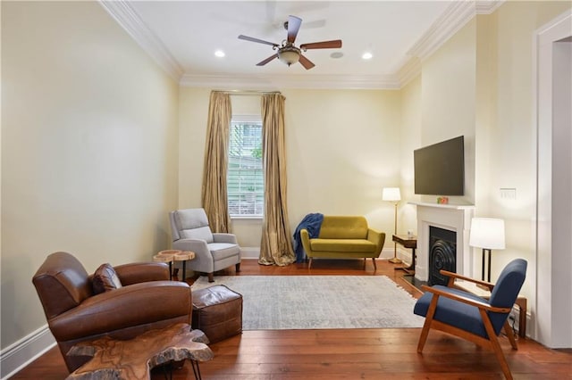 living area featuring ceiling fan, hardwood / wood-style flooring, and crown molding