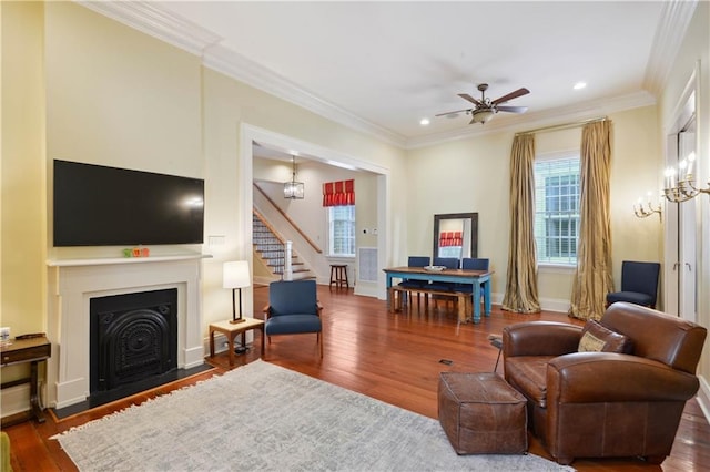 living room with ceiling fan with notable chandelier, dark hardwood / wood-style floors, and crown molding