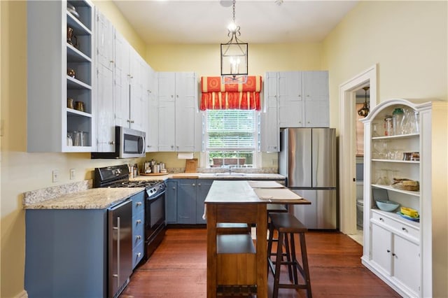 kitchen with appliances with stainless steel finishes, hanging light fixtures, dark wood-type flooring, light stone countertops, and sink