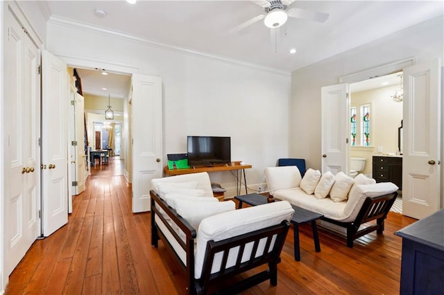 living room with ceiling fan, hardwood / wood-style flooring, and ornamental molding