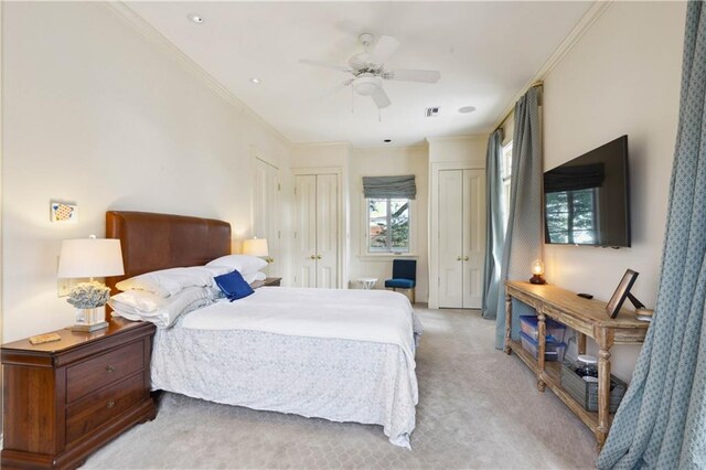 carpeted bedroom featuring multiple closets, ceiling fan, and crown molding