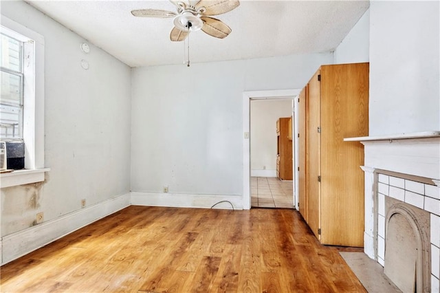 unfurnished living room featuring light wood-type flooring, ceiling fan, and a fireplace