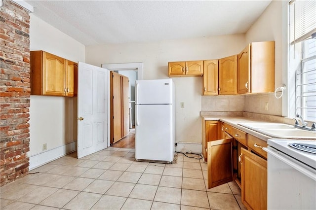 kitchen featuring brick wall, a wealth of natural light, light tile patterned flooring, and white fridge