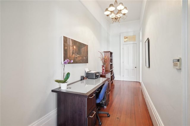 home office with dark hardwood / wood-style floors and a notable chandelier