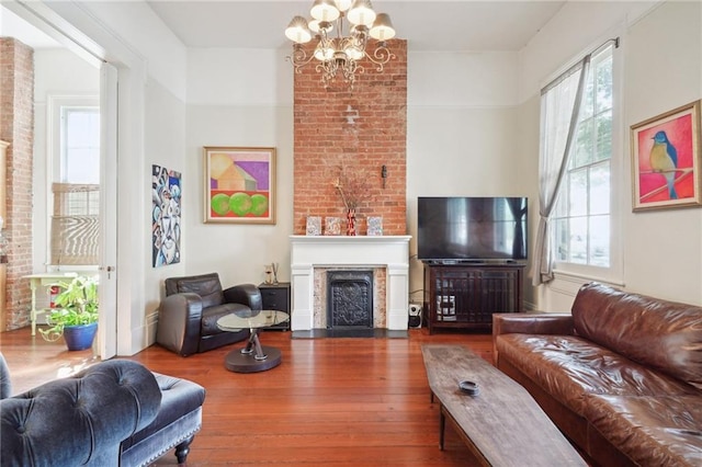 living room with wood-type flooring, a chandelier, and a large fireplace