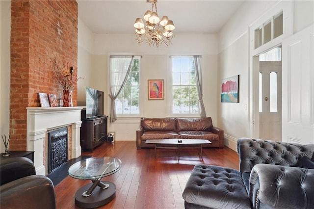 living room with brick wall, dark hardwood / wood-style floors, and a chandelier