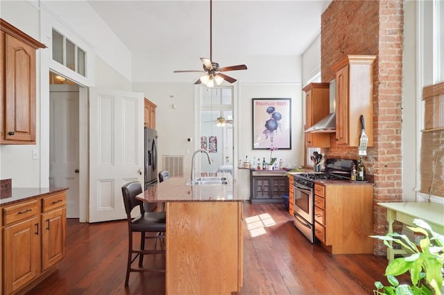 kitchen featuring an island with sink, dark hardwood / wood-style flooring, ceiling fan, and stainless steel appliances