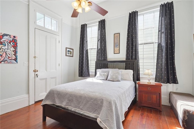 bedroom featuring multiple windows, crown molding, dark hardwood / wood-style flooring, and ceiling fan