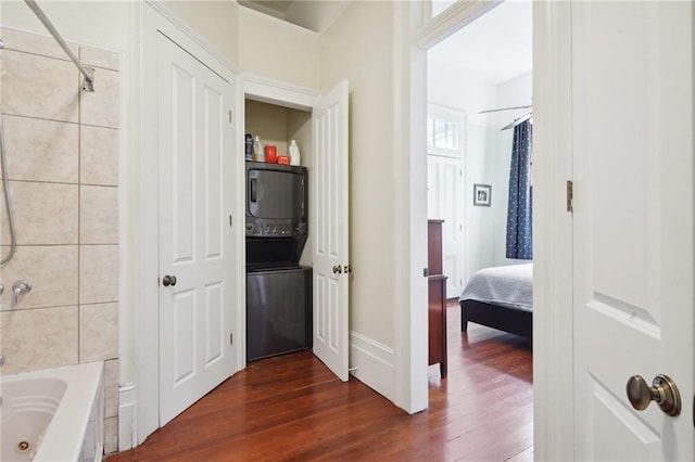 bathroom with stacked washer / dryer, hardwood / wood-style floors, and shower / bath combo