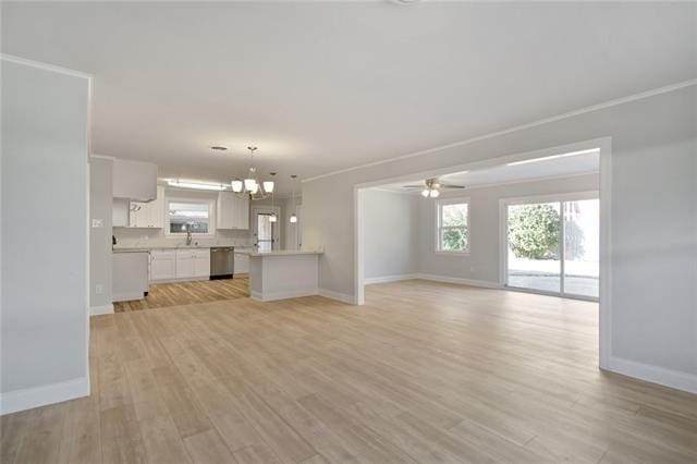 unfurnished living room featuring ceiling fan with notable chandelier, light hardwood / wood-style floors, ornamental molding, and sink