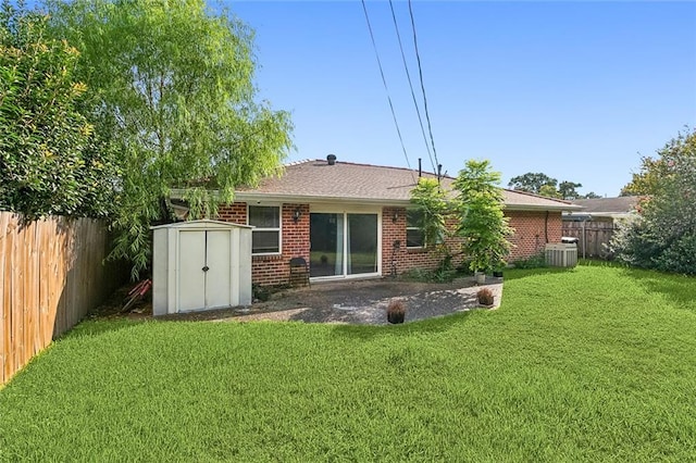 rear view of property featuring central AC unit, a yard, a shed, and a patio area