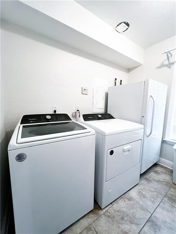 clothes washing area featuring light tile patterned floors, electric panel, and washer and dryer