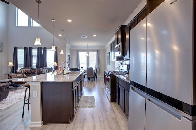 5572 Wake Reserve Rd, Slidell, LA 70461 - kitchen with appliances with stainless steel finishes, light wood-style flooring, a sink, a breakfast bar, and open floor plan