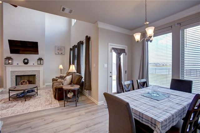 5572 Wake Reserve Rd, Slidell, LA 70461 - dining area featuring light wood-style floors, a chandelier, baseboards, a fireplace, and ceiling fan