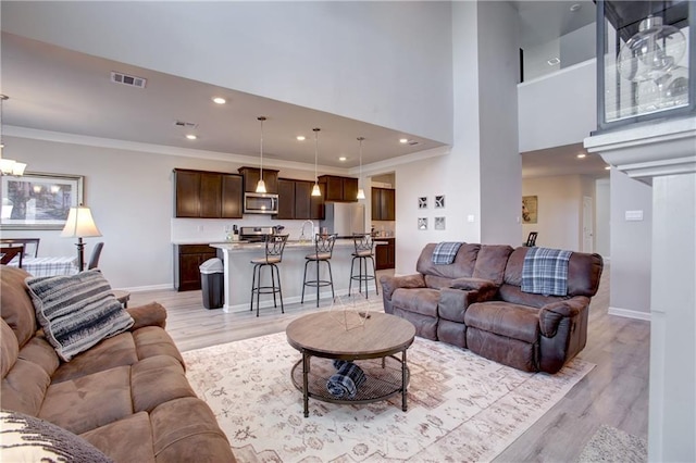 5572 Wake Reserve Rd, Slidell, LA 70461 - living room with light wood-type flooring, baseboards, ornamental molding, recessed lighting, and a high ceiling