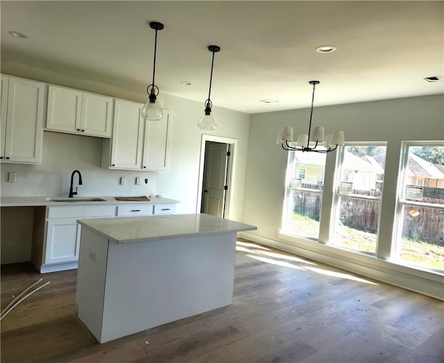 kitchen with white cabinets, wood-type flooring, decorative light fixtures, and sink