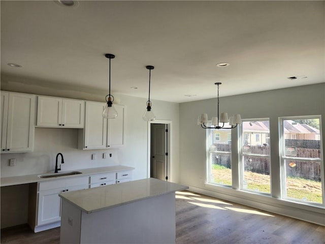 kitchen with hardwood / wood-style flooring, white cabinetry, sink, and hanging light fixtures