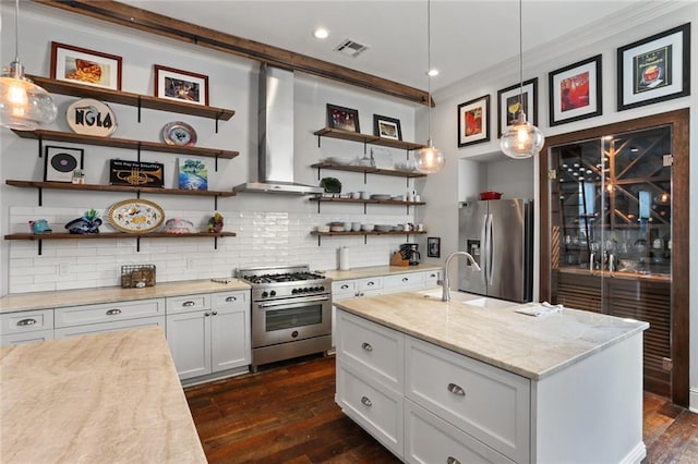 kitchen featuring decorative light fixtures, stainless steel appliances, wall chimney exhaust hood, and white cabinetry