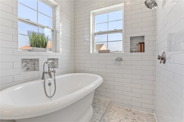 bathroom with tile walls, a tub, and tile patterned floors