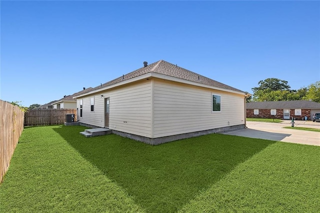 view of side of property featuring a lawn, central AC, and a patio area