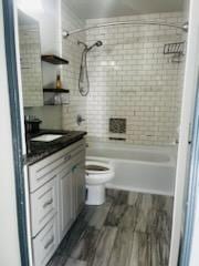 full bathroom featuring wood-type flooring, toilet, vanity, and tiled shower / bath