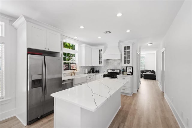 kitchen with stainless steel appliances, a kitchen island, light hardwood / wood-style flooring, white cabinets, and custom exhaust hood