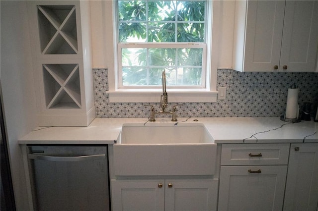 kitchen featuring sink, stainless steel dishwasher, tasteful backsplash, light stone counters, and white cabinetry