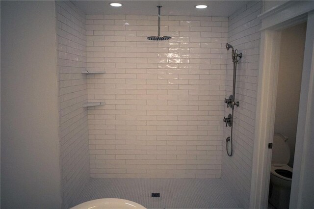 bathroom with a tile shower and toilet