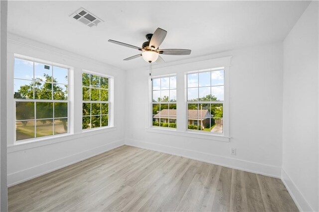 empty room with light hardwood / wood-style floors, ceiling fan, and a healthy amount of sunlight