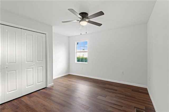 unfurnished bedroom featuring ceiling fan, a closet, and dark wood-type flooring