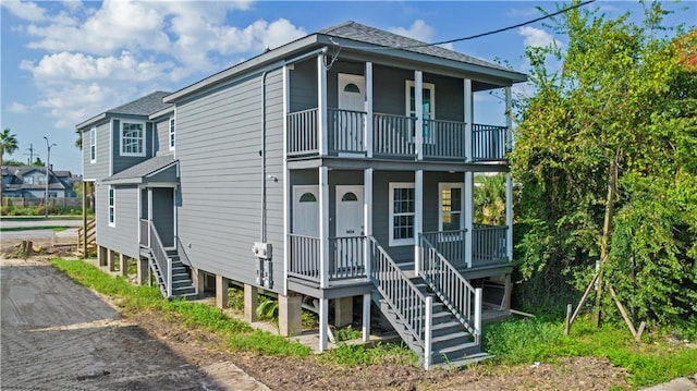 raised beach house featuring a balcony and covered porch