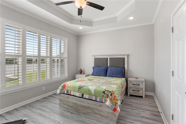 bedroom featuring light wood-type flooring, crown molding, ceiling fan, and a raised ceiling