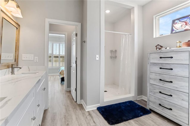 bathroom with a shower with curtain, vanity, wood-type flooring, and plenty of natural light