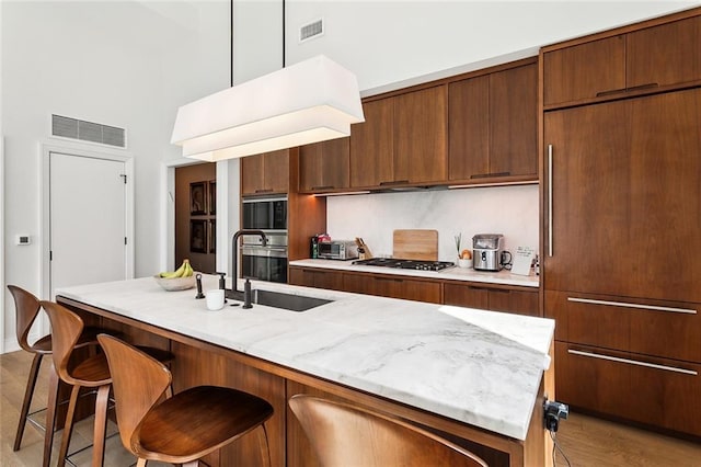 kitchen featuring a kitchen breakfast bar, a center island with sink, pendant lighting, and stainless steel appliances