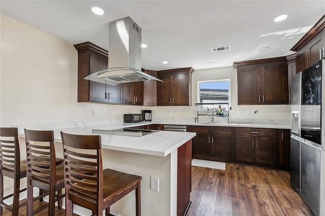 kitchen with a kitchen breakfast bar, black appliances, exhaust hood, and dark hardwood / wood-style floors