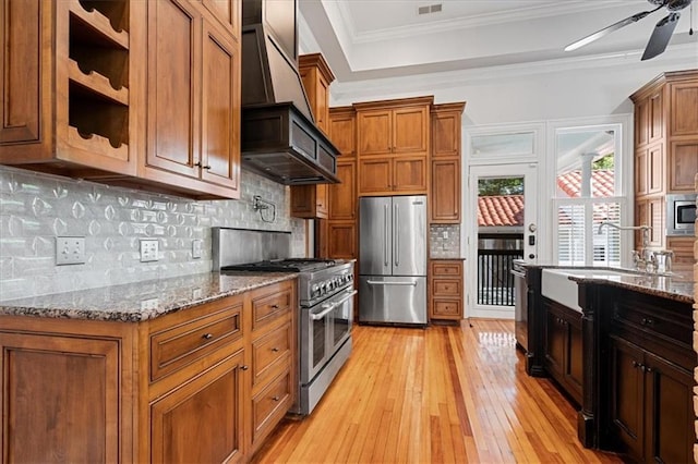 kitchen with light hardwood / wood-style flooring, stainless steel appliances, crown molding, dark stone countertops, and ceiling fan