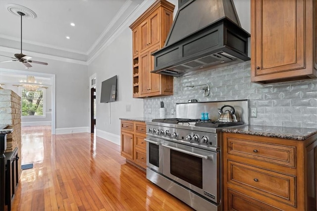 kitchen featuring decorative backsplash, light hardwood / wood-style floors, ceiling fan, double oven range, and premium range hood