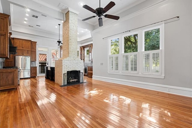 unfurnished living room featuring ornamental molding, light hardwood / wood-style floors, ceiling fan, and a fireplace