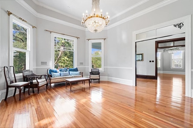 sitting room featuring a healthy amount of sunlight, ornamental molding, wood-type flooring, and a chandelier