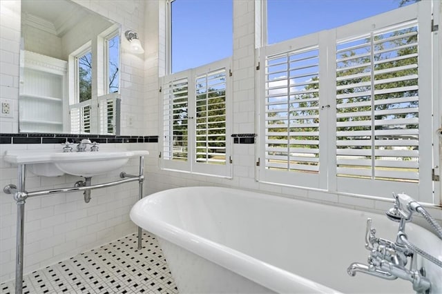 bathroom with a tub to relax in, tile walls, and tile patterned flooring