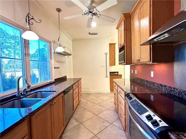 kitchen featuring stainless steel appliances, dark stone counters, pendant lighting, wall chimney exhaust hood, and sink