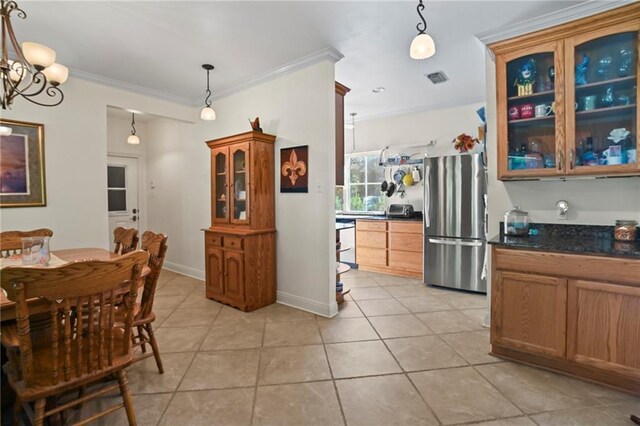 interior space with decorative light fixtures, stainless steel refrigerator, light tile patterned flooring, ornamental molding, and a chandelier