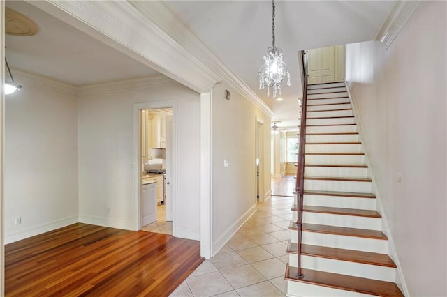 staircase featuring a notable chandelier, hardwood / wood-style flooring, and ornamental molding