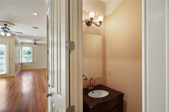 bathroom with crown molding, vanity, hardwood / wood-style floors, and ceiling fan