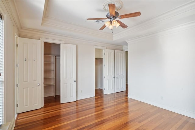 unfurnished bedroom featuring ornamental molding, ceiling fan, a raised ceiling, and hardwood / wood-style floors