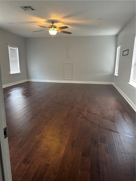 empty room featuring dark wood-type flooring and ceiling fan