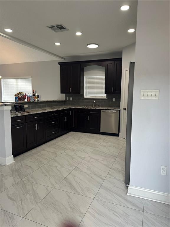 kitchen featuring tasteful backsplash, sink, stainless steel dishwasher, and dark stone counters