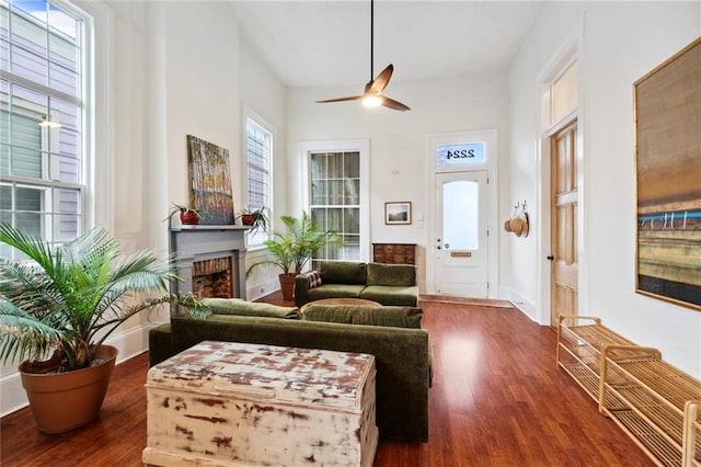 living room with a brick fireplace, ceiling fan, and hardwood / wood-style floors